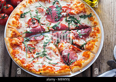 Stein gebackene Pizza mit Salami, Peperoni und Rucola Stockfoto