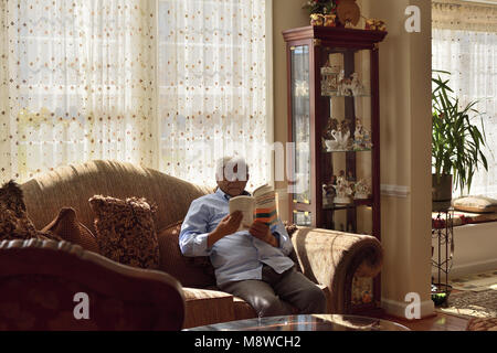 Genießen "Armut und Hungersnöte: ein Essay über den Anspruch und Entbehrungen" von Nobelpreisträger Dr. Amartya Sen, auf einen entspannten Sonntag Nachmittag. Stockfoto