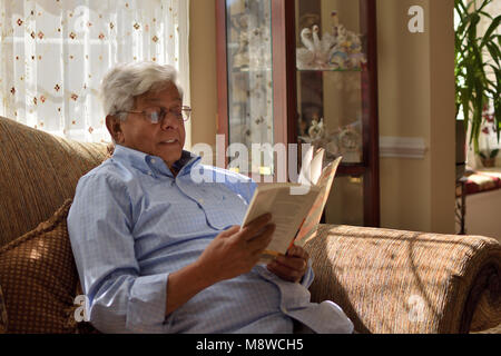 Genießen "Armut und Hungersnöte: ein Essay über den Anspruch und Entbehrungen" von Nobelpreisträger Dr. Amartya Sen, auf einen entspannten Sonntag Nachmittag. Stockfoto