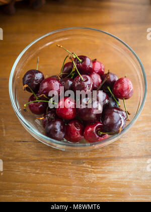 Schwarz frisch frisch gepflückte Kirschen in Schale auf Holztisch. Stockfoto