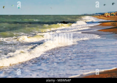 Großen schäumenden Wellen am Strand an einem sonnigen Tag mit der rauen See. Tilt Shift Effekt. Stockfoto