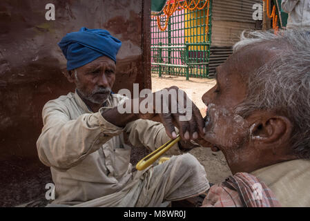 Ein Friseur, ein Mann auf der Straße, Sonepur, Indien zu rasieren. Stockfoto