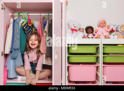 Ein kleines Mädchen sitzt in einem Schrank mit einem Kinder - Abteilung Stockfoto