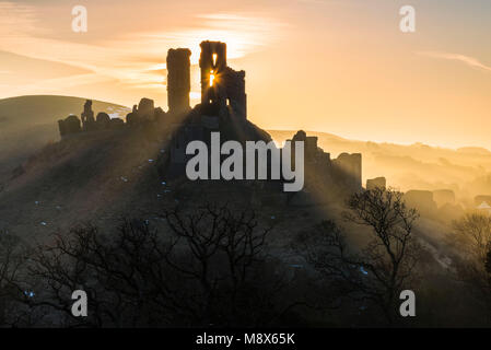 Corfe Castle, Dorset, Großbritannien. 21. März 2018. UK Wetter. Sonnenstrahlen durchscheinen und um die Silhouette der Ruinen von Corfe Castle in Dorset an einem klaren hellen Morgen kurz nach Sonnenaufgang. Foto: Graham Jagd-/Alamy Leben Nachrichten. Stockfoto