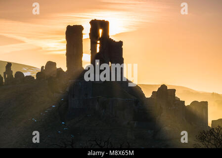 Corfe Castle, Dorset, Großbritannien. 21. März 2018. UK Wetter. Sonnenstrahlen durchscheinen und um die Silhouette der Ruinen von Corfe Castle in Dorset an einem klaren hellen Morgen kurz nach Sonnenaufgang. Foto: Graham Jagd-/Alamy Leben Nachrichten. Stockfoto