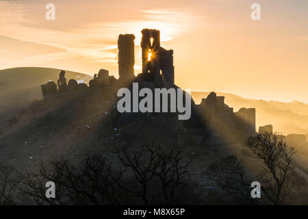 Corfe Castle, Dorset, Großbritannien. 21. März 2018. UK Wetter. Sonnenstrahlen durchscheinen und um die Silhouette der Ruinen von Corfe Castle in Dorset an einem klaren hellen Morgen kurz nach Sonnenaufgang. Foto: Graham Jagd-/Alamy Leben Nachrichten. Stockfoto