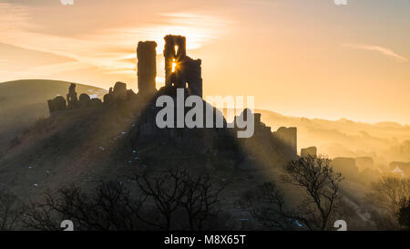 Corfe Castle, Dorset, Großbritannien. 21. März 2018. UK Wetter. Sonnenstrahlen durchscheinen und um die Silhouette der Ruinen von Corfe Castle in Dorset an einem klaren hellen Morgen kurz nach Sonnenaufgang. Foto: Graham Jagd-/Alamy Leben Nachrichten. Stockfoto