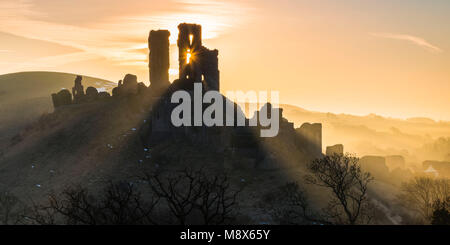 Corfe Castle, Dorset, Großbritannien. 21. März 2018. UK Wetter. Sonnenstrahlen durchscheinen und um die Silhouette der Ruinen von Corfe Castle in Dorset an einem klaren hellen Morgen kurz nach Sonnenaufgang. Foto: Graham Jagd-/Alamy Leben Nachrichten. Stockfoto