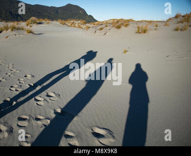 Touristen die Schatten auf den Strand bei Martins Bay, Fjordland, Neuseeland Stockfoto