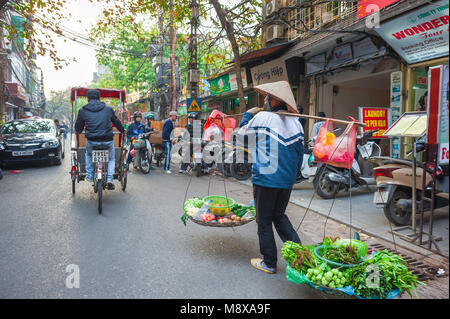 Hanoi Old Quarter, Rückansicht einer Verkäuferin, die Gemüse durch die Straßen der historischen Altstadt im Zentrum von Hanoi, Vietnam, transportiert. Stockfoto