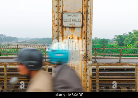 Long Bien Brücke Hanoi, Verkehrsströme hinter einer Säule auf der Long Bien Brücke Lager das Typschild der französische Ingenieure, die es gebaut, Vietnam. Stockfoto