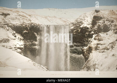 Skogafoss, die großen und schönen Wasserfall in Island im Winter. Snow Blizzard in Island in der Nähe von berühmten Wasserfall Skogafoss. Stockfoto