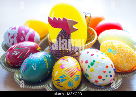 Auf das Fach sind Handbemalte Ostereier mit einem Korb mit Henne aus Weidenruten. Stockfoto