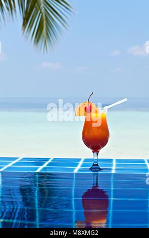 Glas orage Saft ist an der Kante der Pool aus glasierten Fliesen in Tropical Hotel gemacht, Malediven Stockfoto