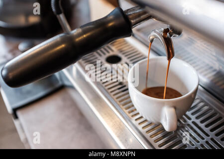 Frischen espresso tropft vom portafilter der Kaffeemaschine in weißen Schale Stockfoto