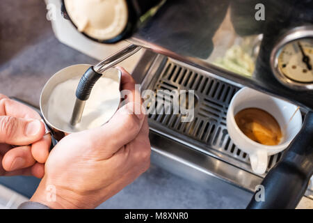 Barista dämpfen und Aufschäumen der Milch in Edelstahl Zuhaltung mit Espresso maching für Cappuccino oder Latte Stockfoto