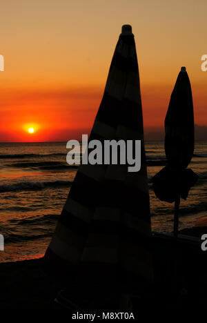 Sommer Meer, Sonnenschirm bei Sonnenuntergang am Strand geschlossen, Konzept für den Beginn der Nacht, vertikal Stockfoto