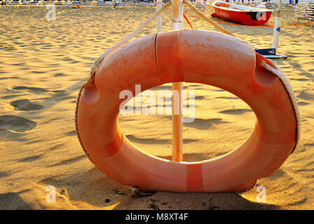 Sommer Meer, bis auf orangefarbenen Rettungsring am Strand in der Nähe, selektiver Fokus, im Hintergrund das Bereitschaftsboot Stockfoto