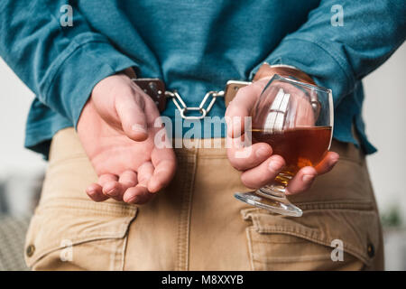 Junger Mann im Wohnzimmer Alkoholproblemen Hände hinter in Handschellen Slave der Sucht close-up Stockfoto