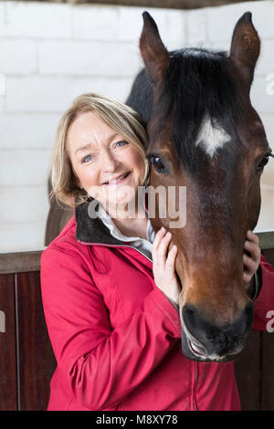 Portrait von Reife weibliche Besitzer in stabilen mit Pferd Stockfoto