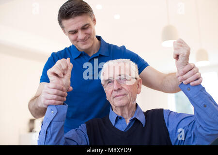 Männliche Krankenschwester Bewertung Senior Schlaganfall Opfer durch Anheben der Arme Stockfoto