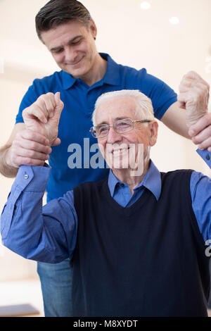 Männliche Krankenschwester Bewertung Senior Schlaganfall Opfer durch Anheben der Arme Stockfoto