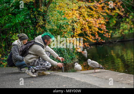 Irish Punk paar Fütterung Vögel im Park Stockfoto