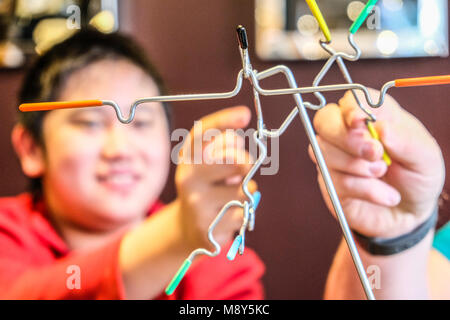 Ein autistischer Junge spielt Magnetische balancing Sticks mit einem Berater an einem Spiel Zimmer Stockfoto