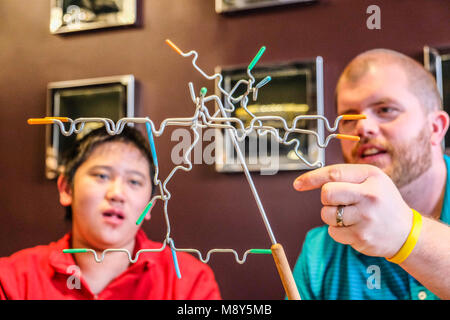 Ein autistischer Junge spielt Magnetische balancing Sticks mit einem Berater an einem Spiel Zimmer Stockfoto