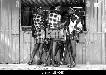 Junge Hamar Männern außerhalb ein Mobiltelefon (Handy) Shop während Ihrer wöchentlichen Besuch der Stammes- Markt in Dimeka, Omo Valley, Äthiopien Stockfoto