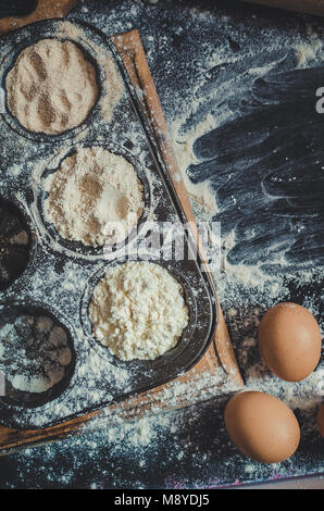 Andere Art von Mehl. Verschiedene Arten von Mehl in Metall backen Form mit Eiern auf dunklen Tisch. Backen Konzept. Ansicht von oben. Vertikale. Kopieren Sie Platz. Stockfoto