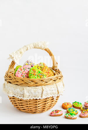 Buntes Osterfest Cookies in einem Korb auf weißem Hintergrund. Easter egg Cookies. Hausgemachte Lebkuchen Kekse in der Form der Ostereier. Platz für t Stockfoto