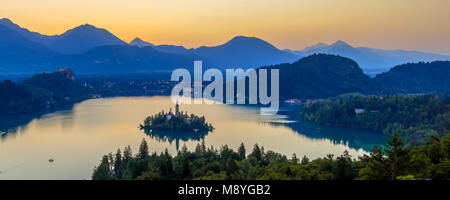 Antenne frühen mornng Blick auf See mit berühmten Sehenswürdigkeiten Kirche auf der Insel bei Sonnenaufgang über die Julischen Alpen Bled. Slowenien, Europa Stockfoto
