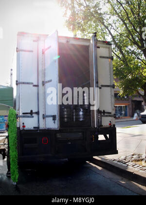 Eine Sammlung von silbernen Bierfässer angehäuft zusammen in der Rückseite eines offenen Lkw geparkt auf eine Stadt Kandare mit späten Nachmittag sunbeams Streaming durch. Stockfoto