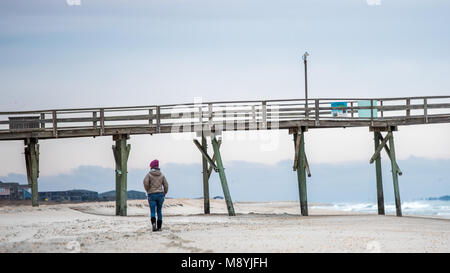Frau zu Fuß am Strand ein Sonnenaufgang mit dem Atlantic Beach Pier im Hintergrund mit Sand, das Meer, die Wellen und die blauen Wolken Stockfoto