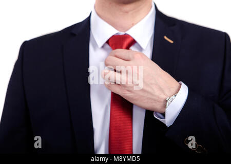 Junge Geschäftsmann zur Festsetzung seiner rote Krawatte, Hochzeit Riegel, close-up vor weißem Hintergrund. Stockfoto