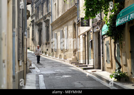 Alte lokale Mann am frühen Morgen auf einer schmalen Seitenstraße in der Altstadt von Arles. Frankreich Stockfoto