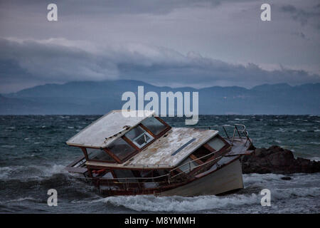 Eine verlassene Fischerboot an der Küste von Asyl links - Asylbewerber und Flüchtlinge in Griechenland ankommen. Im Jahr 2015 mehr als eine Million Einwanderer in Europa, die auf dem Seeweg angekommen. Die Einwanderer sind vor allem Flüchtlinge, die den Krieg geflohen sind in Syrien. Stockfoto