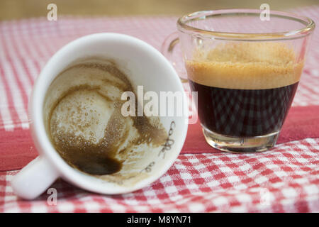 Cremige extra starken Kaffee in ein Glas Schale auf eine farbige Tischdecke Stockfoto