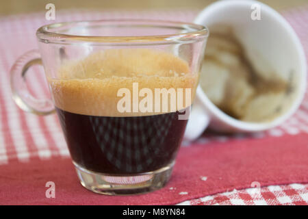 Cremige extra starken Kaffee in ein Glas Schale auf eine farbige Tischdecke Stockfoto