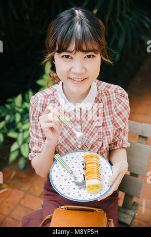 Asiatische Mädchen Jugendliche hipster Glückliches essen Dessert kuchen Roll Stockfoto