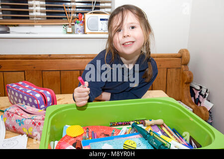 Junges Mädchen saß am Tisch mit Färbung Stifte Stockfoto