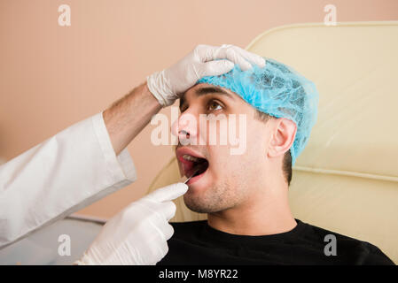 Hno-Arzt checkup Mann die Kehle mit Spachtel Stockfoto