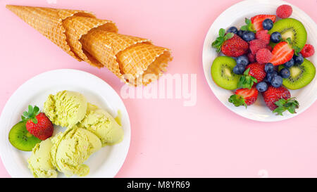Mit Matcha grüner Tee Eis mit Waffeln und frische Früchte auf rosa Holz Tisch, Overhead flach. Stockfoto