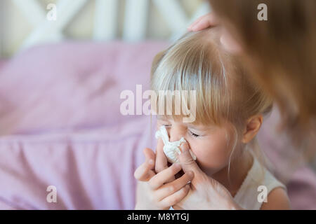 Kind mit Schnupfen. Mutter helfen Kid's Nase mit Papiertuch in die Luft zu sprengen. Saisonale Krankheit. Stockfoto