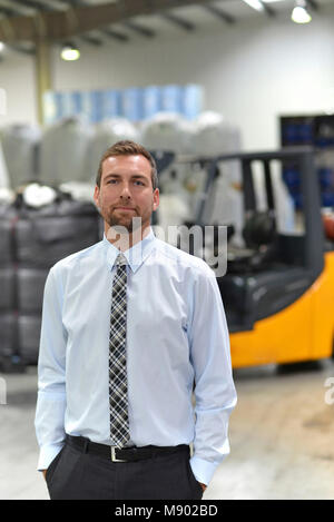 Porträt eines Managers in einem Logistik Unternehmen - im Hintergrund ein Lager mit Chemikalien und waren einer chemischen Fabrik Stockfoto