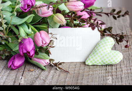 Schönen Blumenstrauß rosa und violett Tulpen mit ein Herz und eine weiße Kopie Speicherplatz auf einem hölzernen Hintergrund Stockfoto
