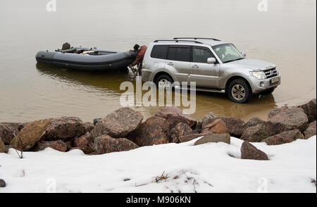 St. Petersburg, Russland - März 05, 2016: Der Mensch ist aus dem Auto Mitsubishi Pajero das Boot auf dem Teich mitgebracht hatte, freigegeben Stockfoto