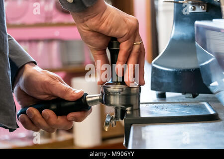 Barista drücken frisch gemahlenen Kaffee mit Stampfer in portafilter Cappuccino oder Espresso zu machen. Stockfoto