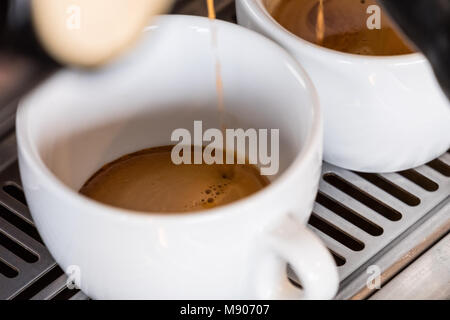 Frischen espresso tropft vom portafilter der Kaffeemaschine in weißen Schale Stockfoto